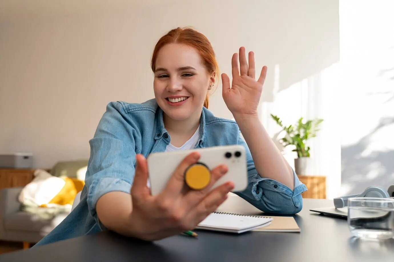 Porträt einer Frau, die zu Hause ein Smartphone mit Pop-Socket benutzt.