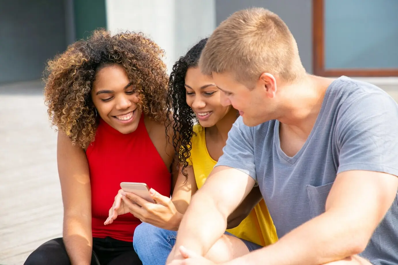 Fröhliche junge Menschen, die ein Smartphone nutzen.